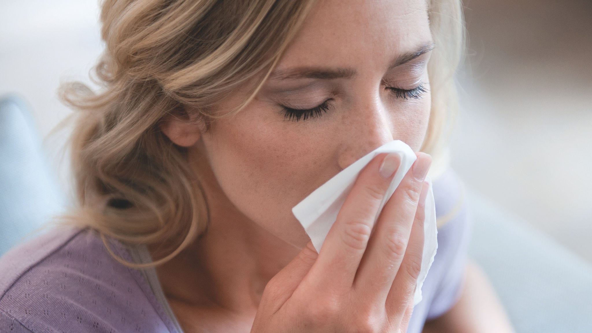 Mulher a assoar o nariz devido à alergia ao pólen