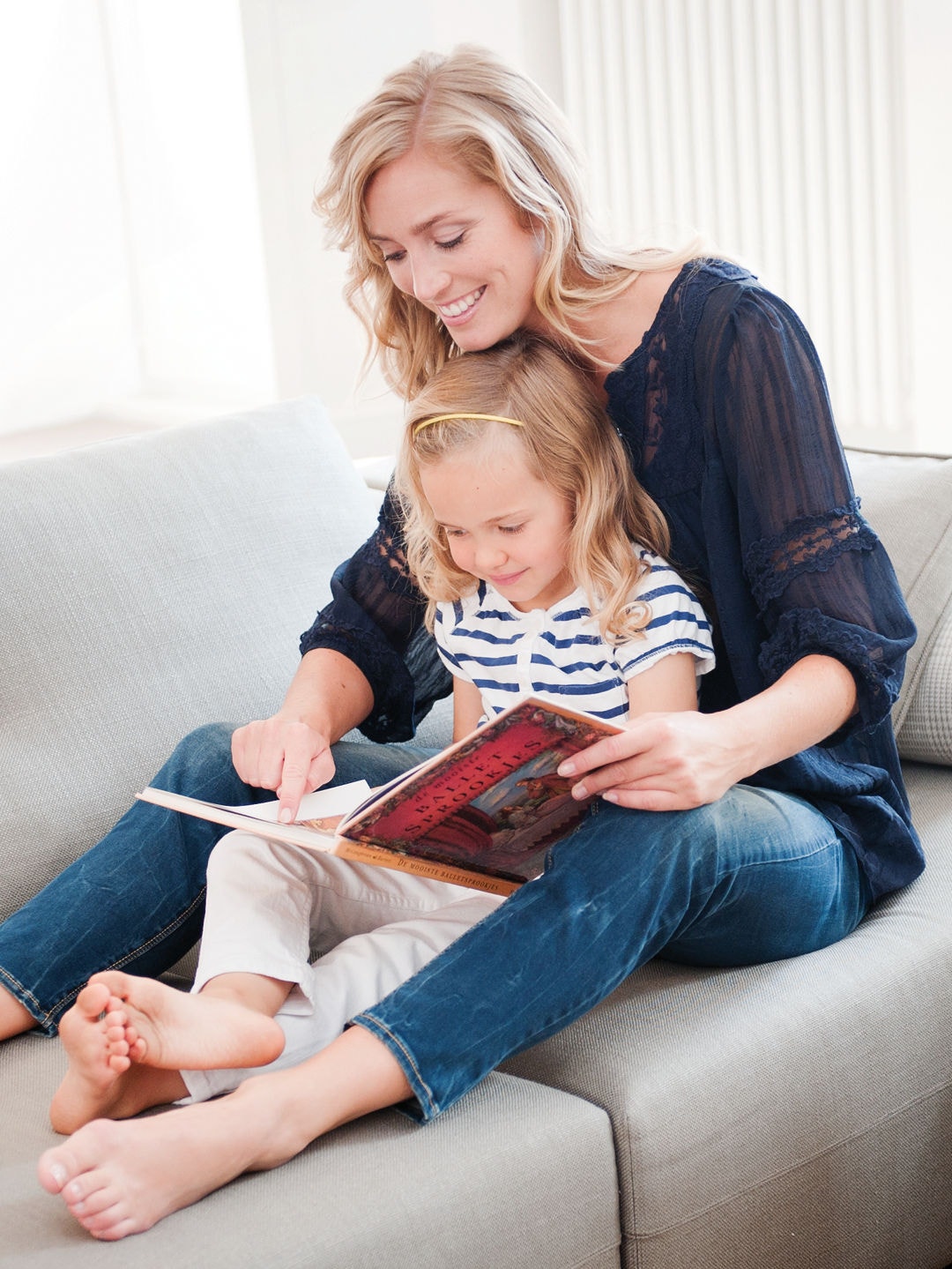 Mãe e filha, sentadas no sofá a ver um livro, usufruindo do ar limpo do Purificador de ar Daikin