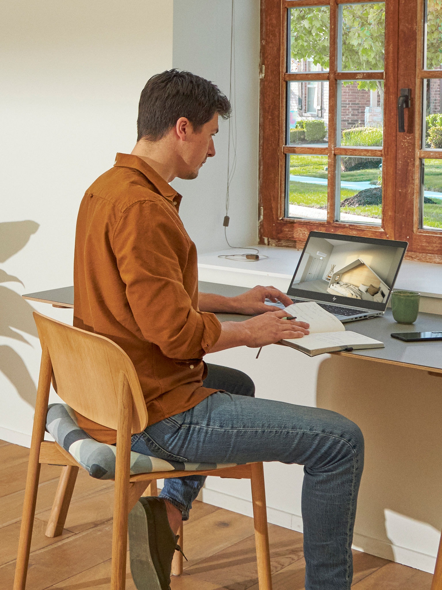 Homem sentado à secretária a visualizar sistemas de ar condicionado no centro de experiência virtual no seu computador portátil