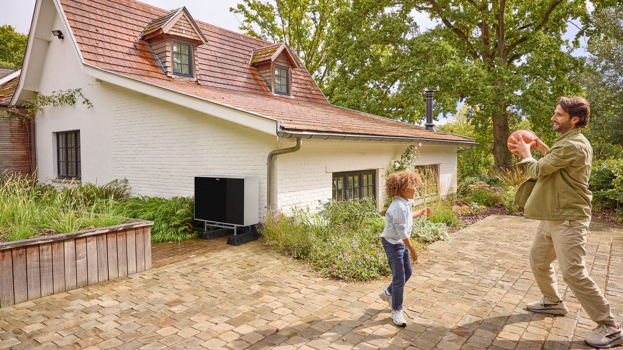 Pai a jogar à bola com o filho no exterior, com uma bomba de calor instalada nas proximidades