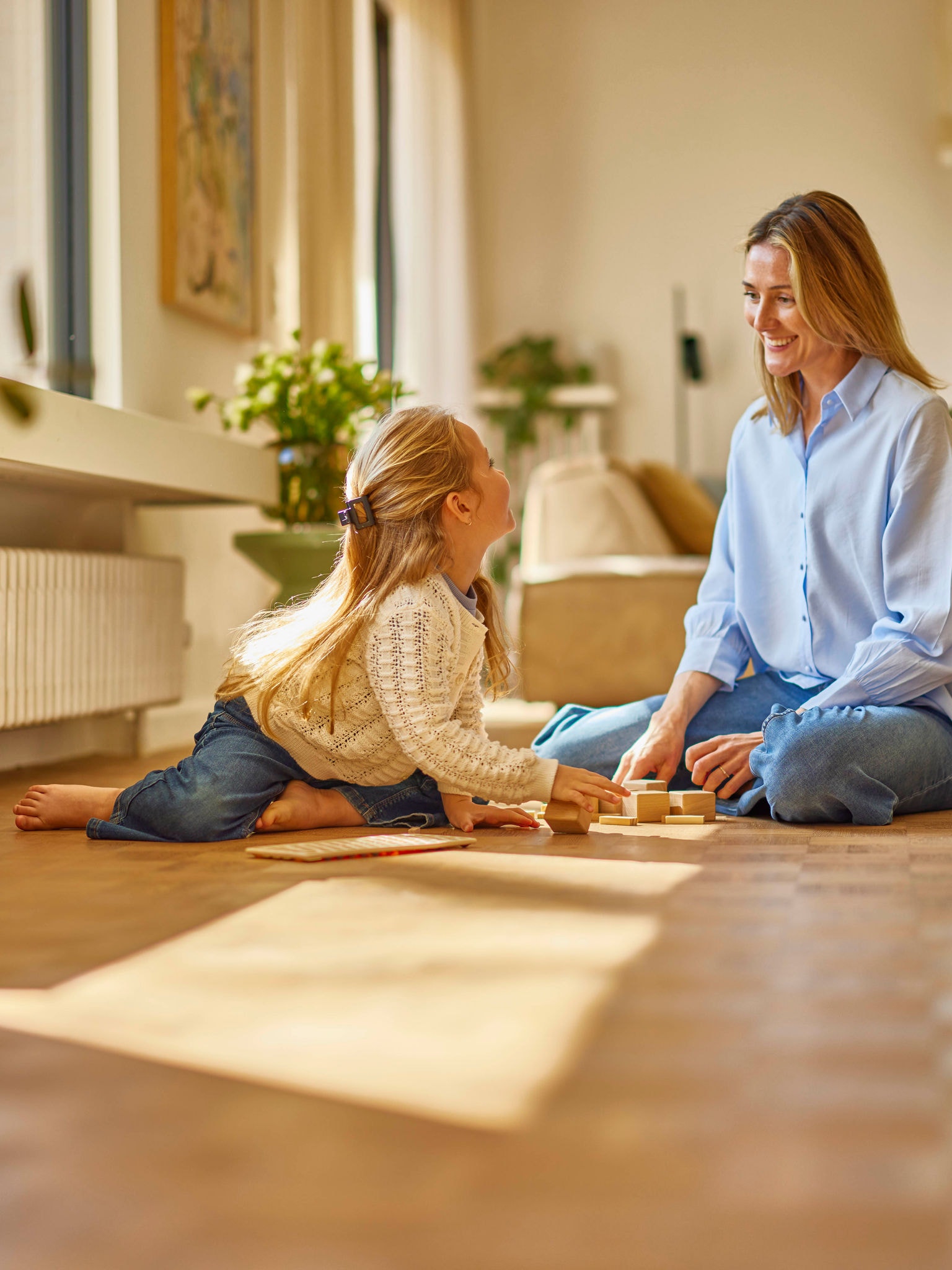 Menina brincando com a mãe, numa sala climatizada com uma unidade Bomba de calor Daikin