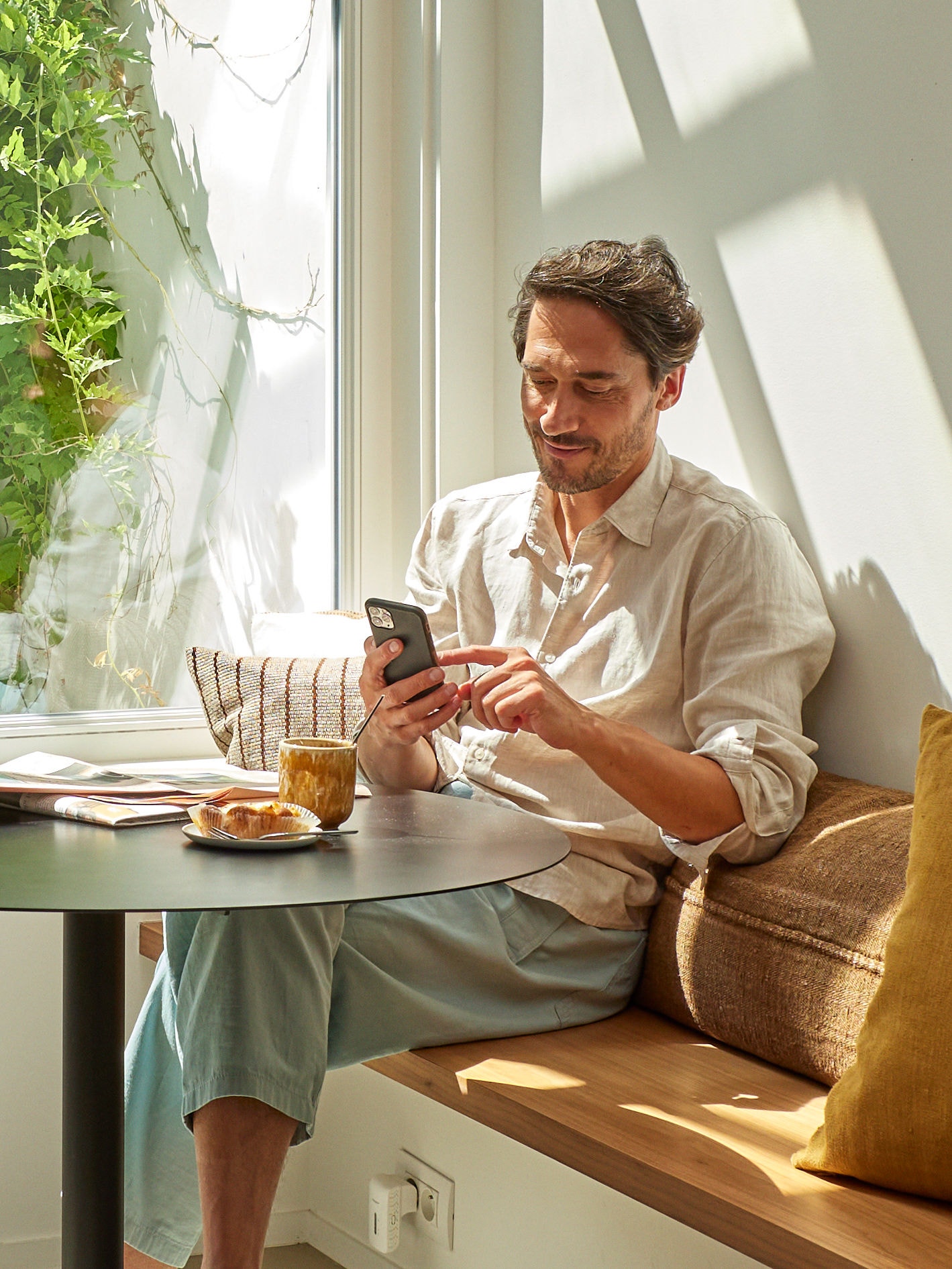 homem durante o pequeno almoço mexendo no smartphone