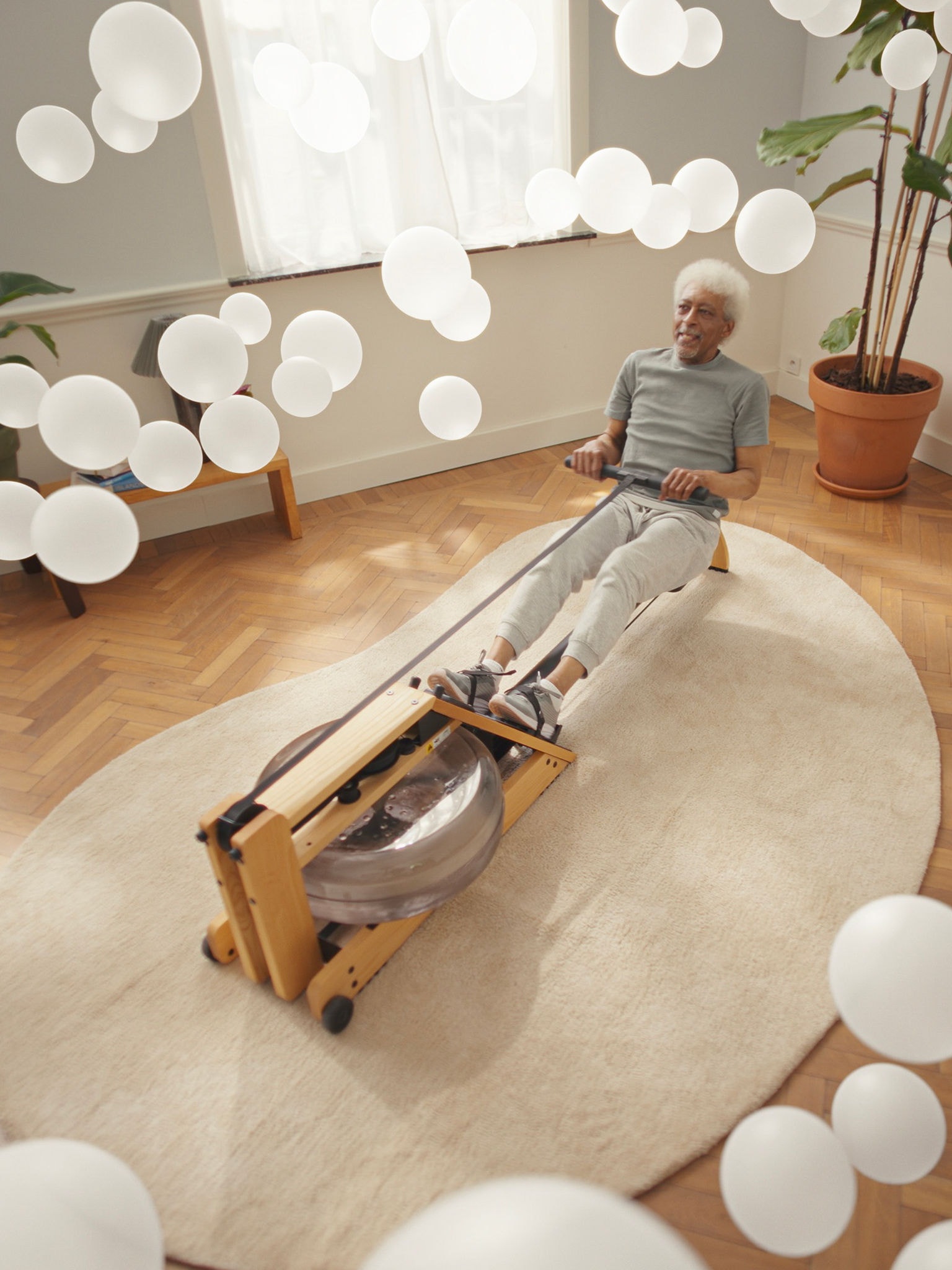 Homem mais velho a fazer exercício numa máquina de remo num ambiente de ar limpo, apoiado por um purificador de ar