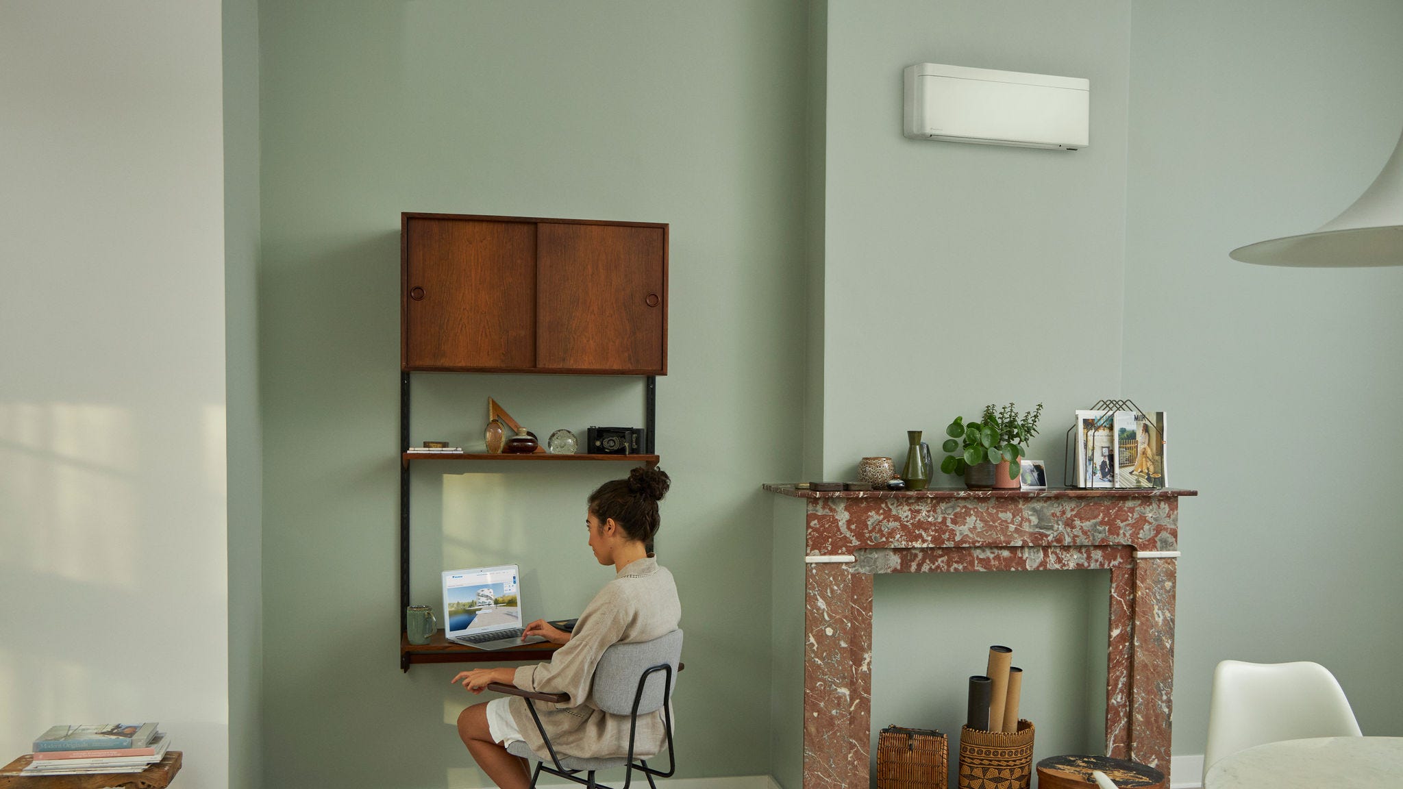 Mulher a visitar o Centro de Experiência Virtual da Daikin através do portátil numa pequena secretária na sala de estar com uma bonita decoração